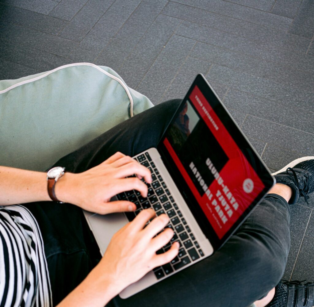 Person working remotely on a laptop while sitting comfortably on a beanbag chair indoors.